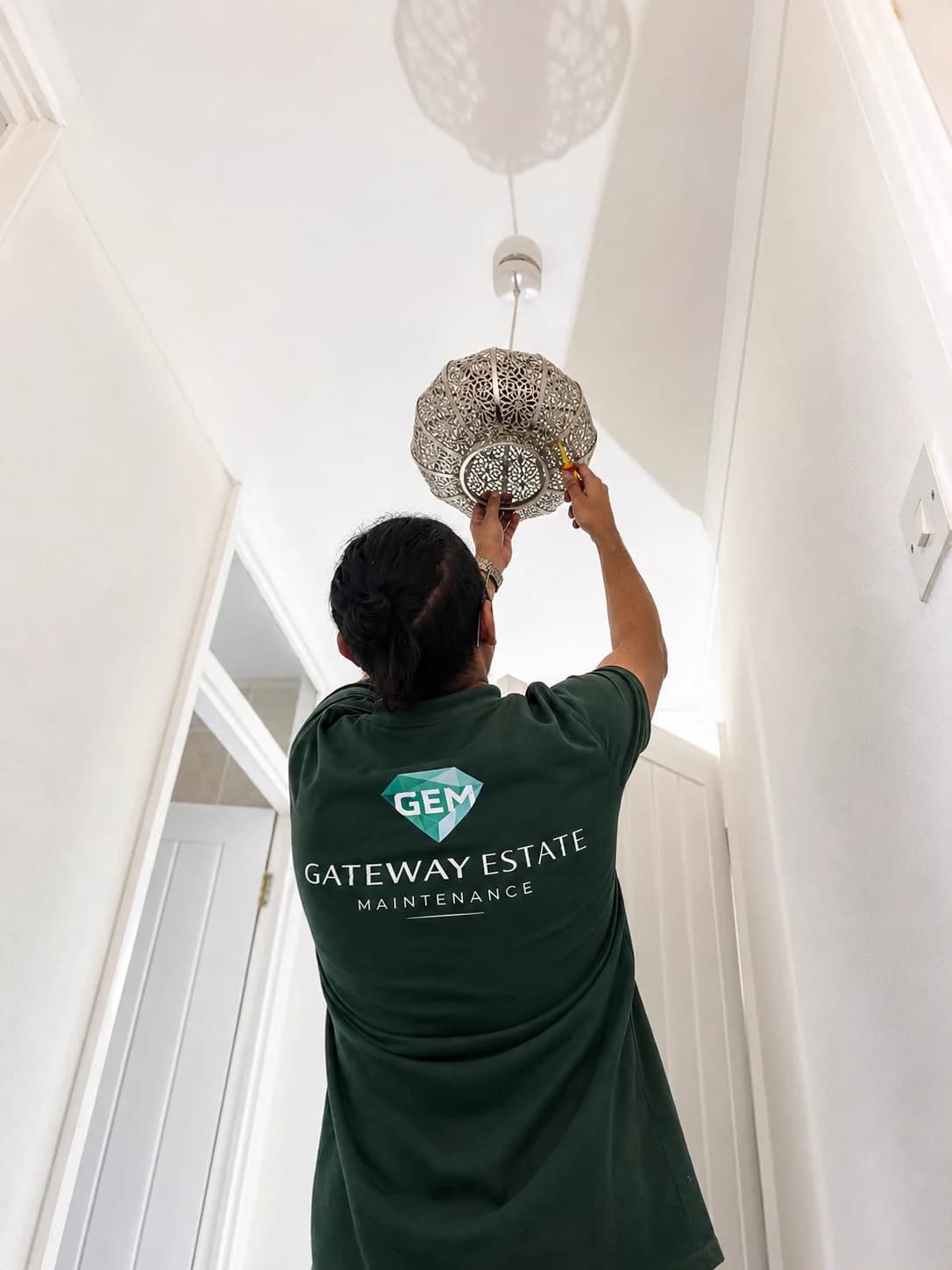 GEM team member fitting a decorative ceiling light shade.