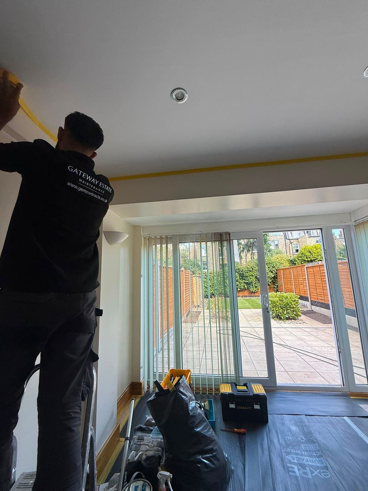GEM decorator masking the ceiling line of a reception room before painting