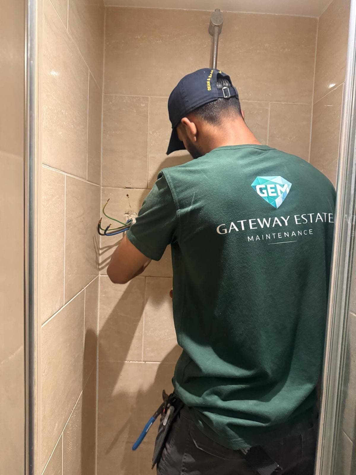 GEM electrician wiring a shower unit in a tiled bathroom